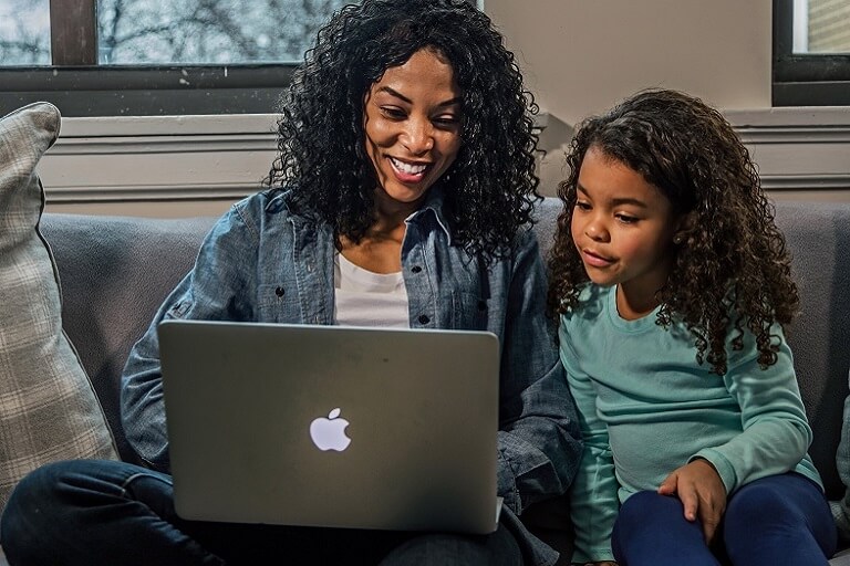 mom with daughter working on laptop from a couch