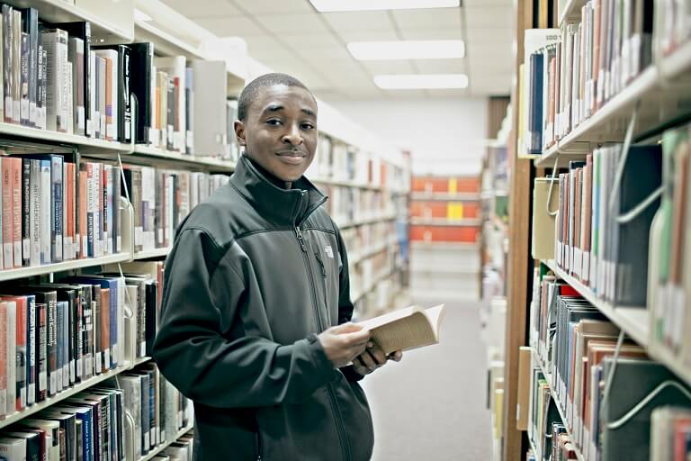 african american male reading book in library