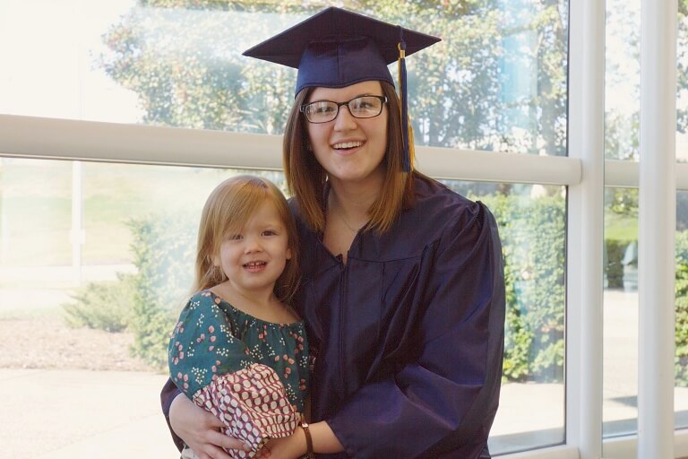 Female graduate with little girl