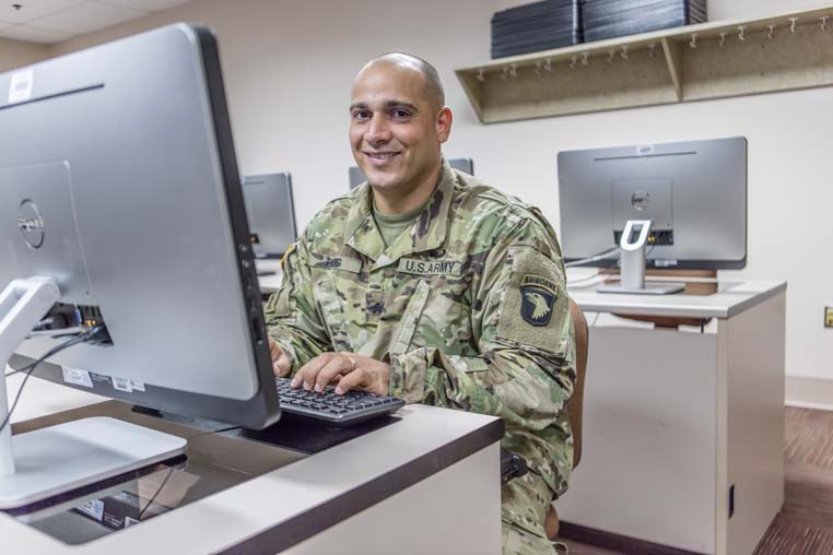 Student in military uniform working on computer. 