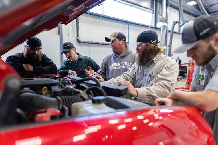 Group of students looking at a diesel engine. 