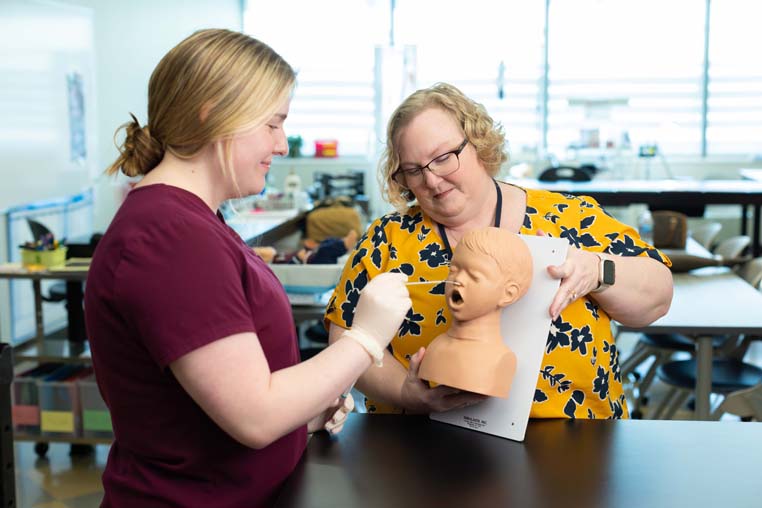Medical student practicing doing a nasal swab on a manakin head. 