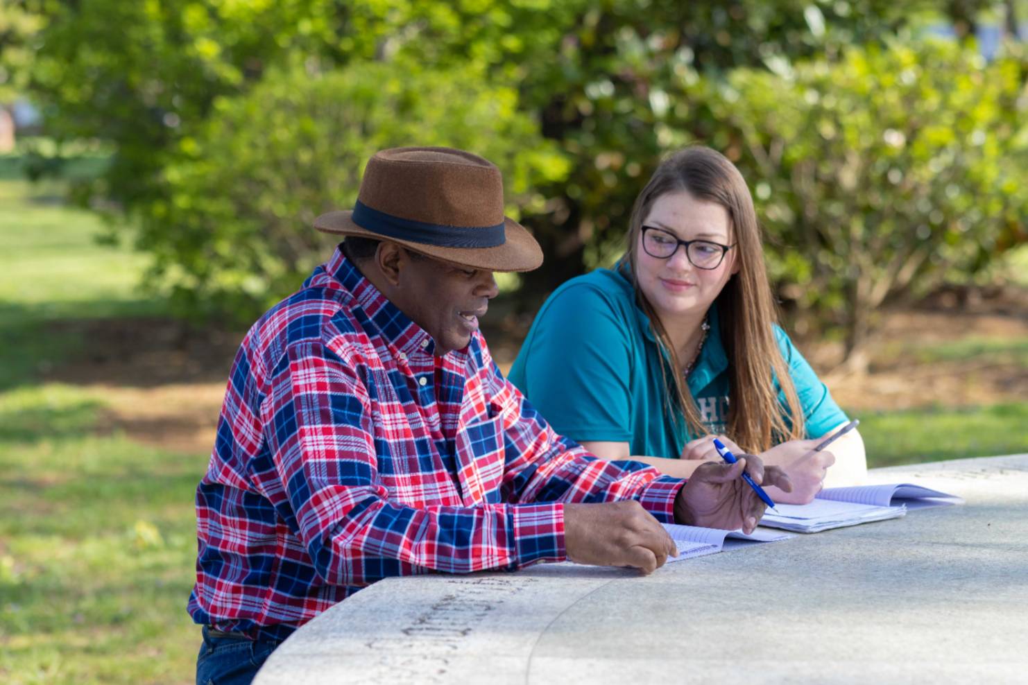 student sitting in round table park with professor