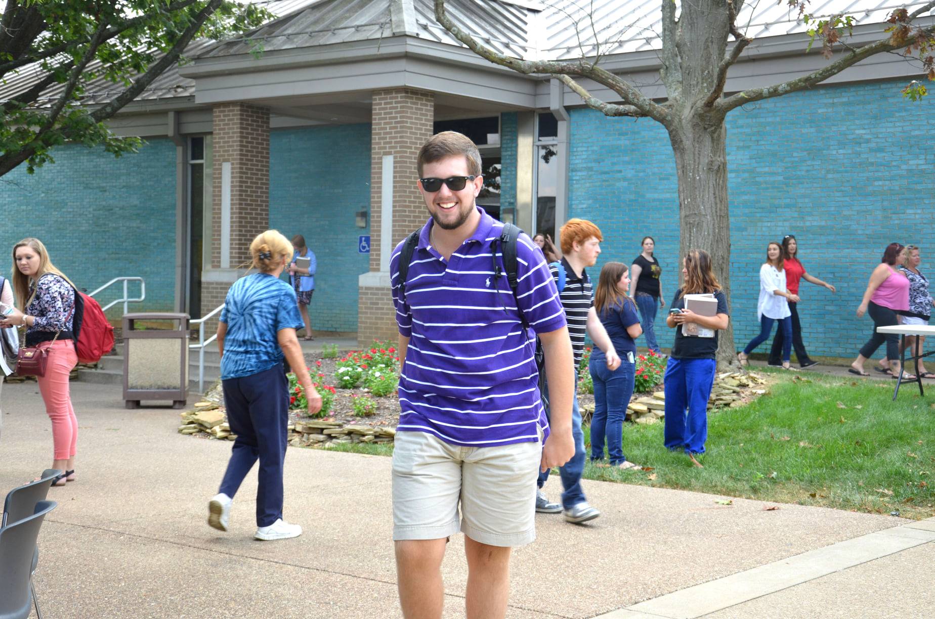 Male walking on campus with additional students in background