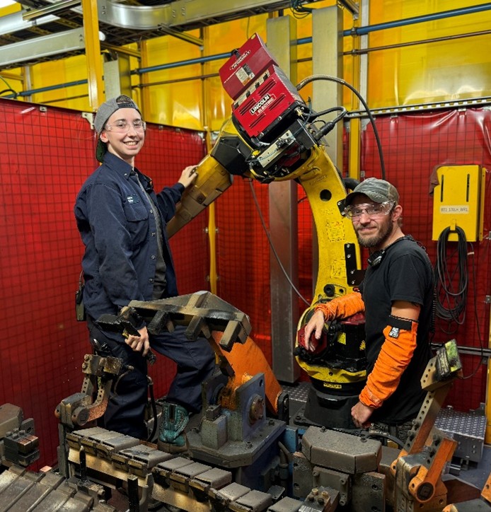 2 students working on a large machine in a workplace
