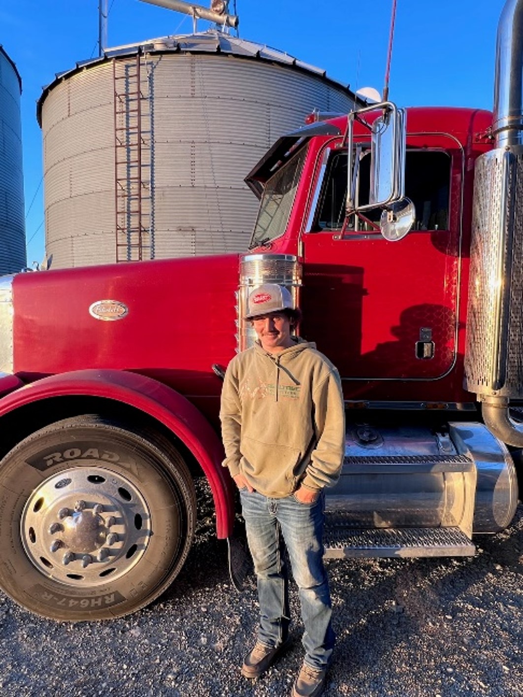 Person standing beside a red semi truck.